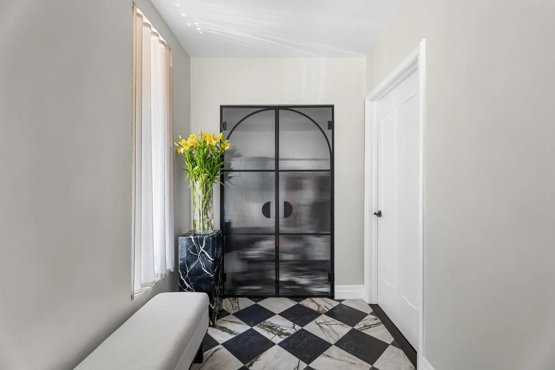 Arched glass shower enclosure and patterned stone floor