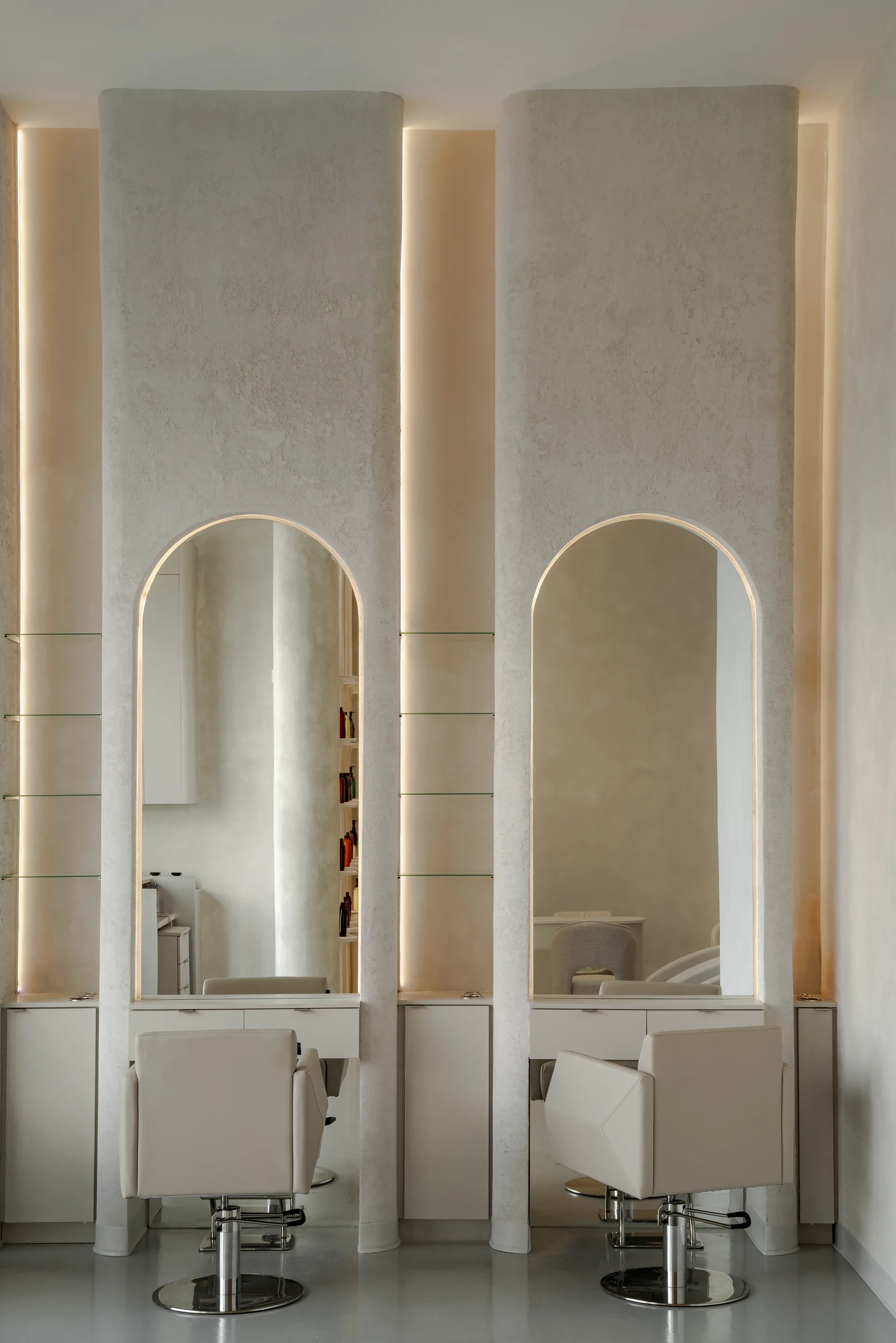 Paired arched mirrors and softly lit wall panels