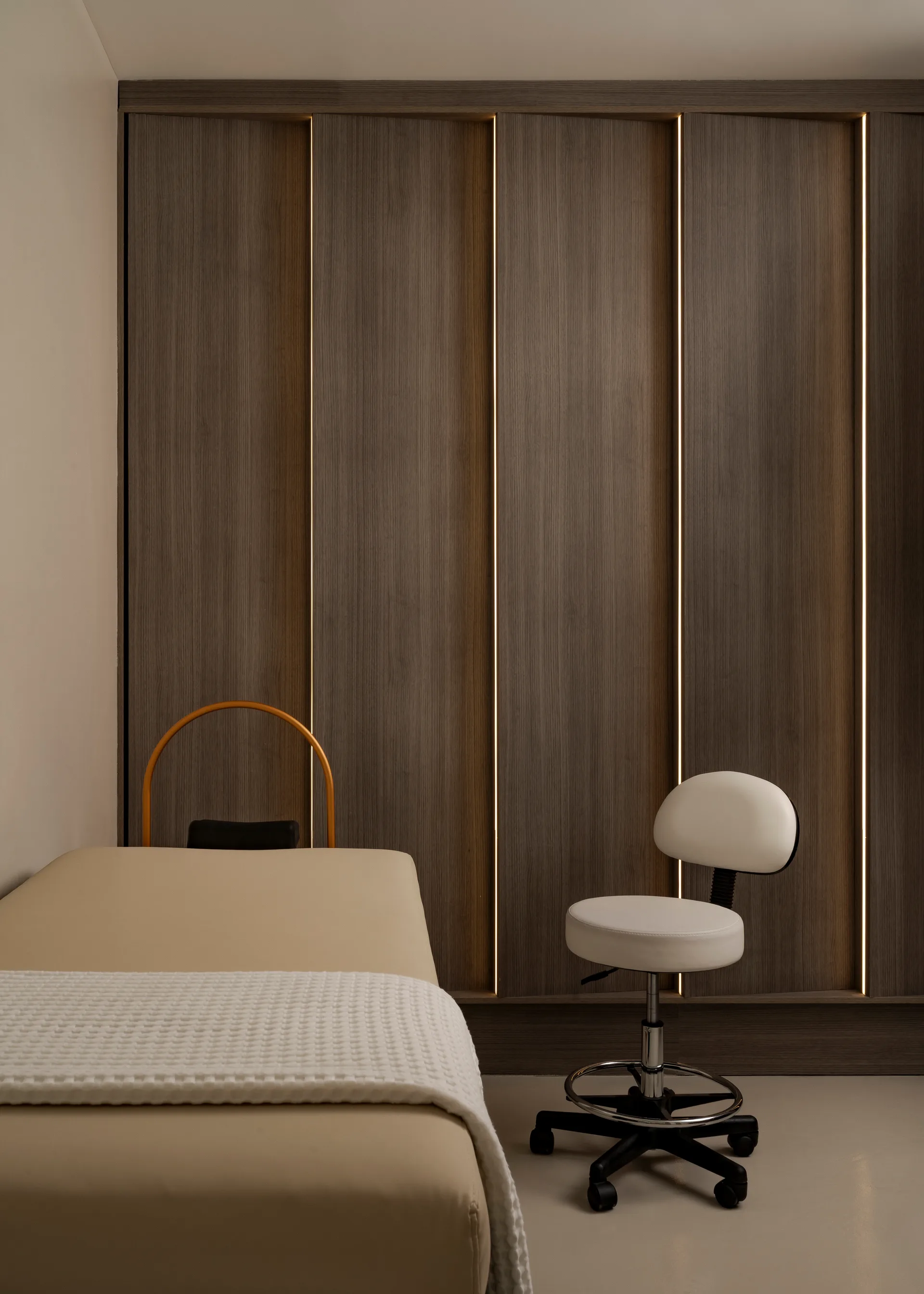 Treatment bed beside a dark timber wardrobe