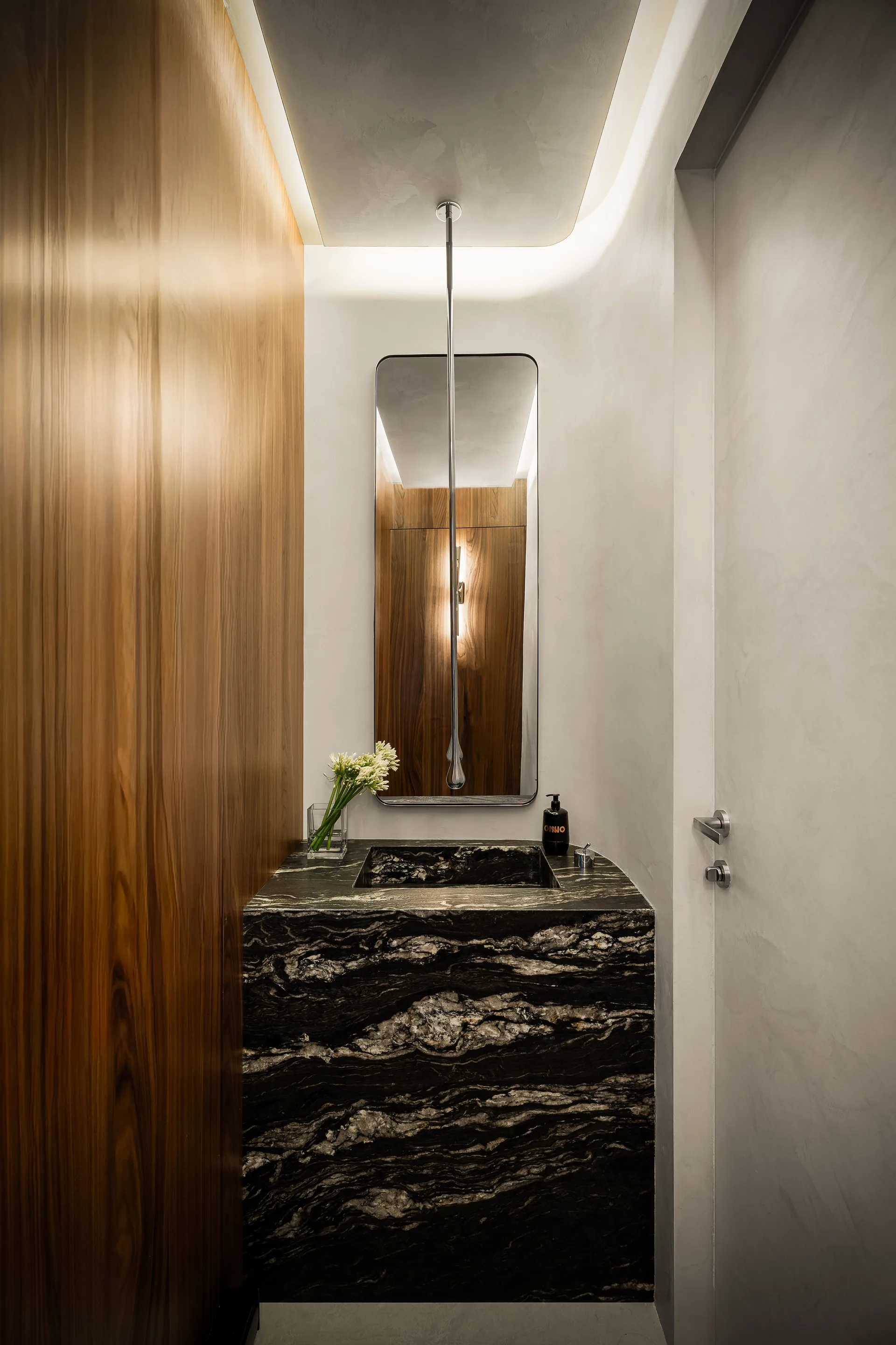 Dark stone vanity, tall mirror and curved lighting