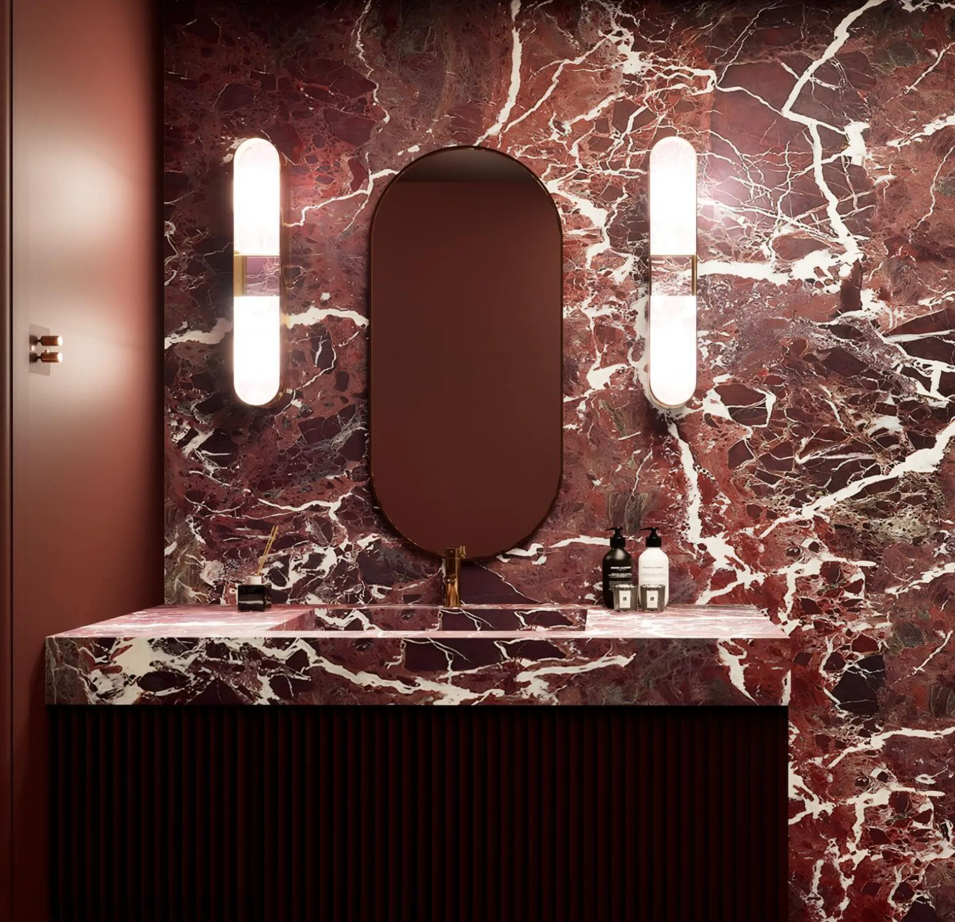 Burgundy marble vanity with an oval mirror and paired wall lights